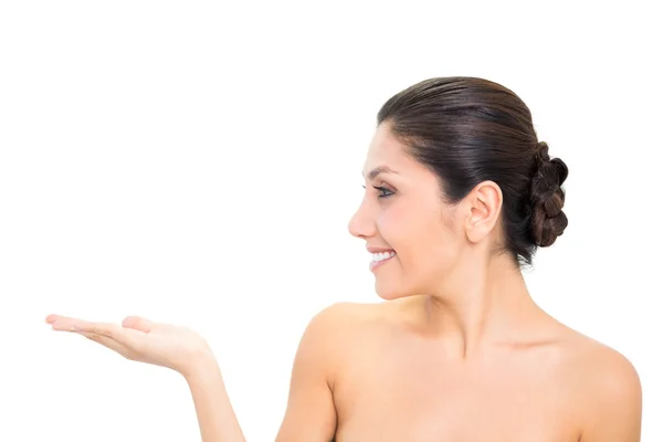 Smiling brunette presenting with hand with head turned — Stock Photo, Image