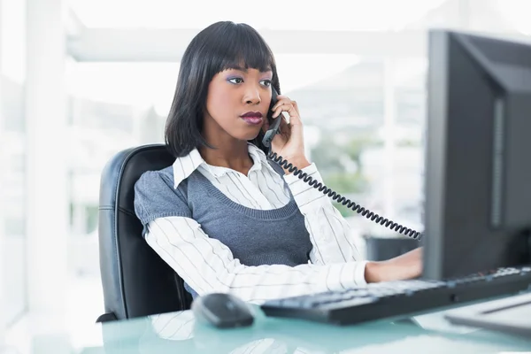 Femme d'affaires sérieuse au téléphone tout en travaillant sur ordinateur — Photo