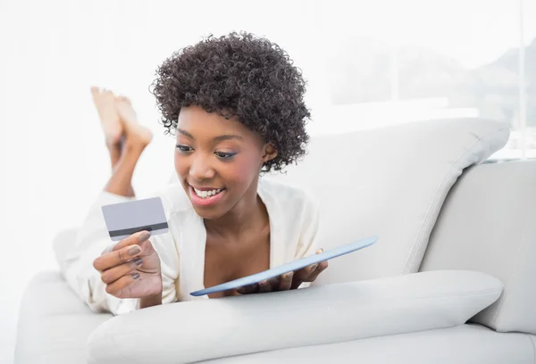 Happy gorgeous brunette shopping online using her tablet — Stock Photo, Image