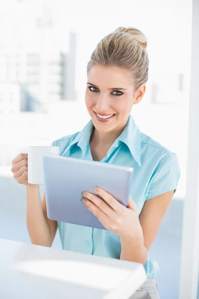 Sorridente donna elegante utilizzando tablet contenente caffè — Foto Stock