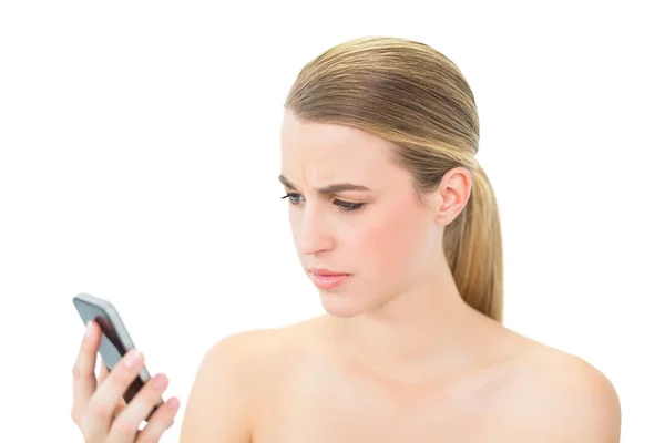 Stirnrunzeln attraktive Blondine schaut auf ihr Smartphone — Stockfoto