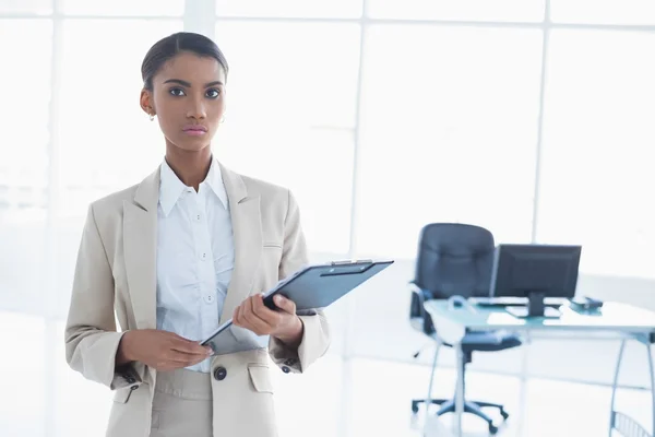 Stern elegant businesswoman holding clipboard — Stock Photo, Image