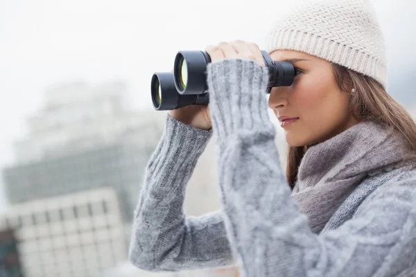 Nádherná žena s zimní oblečení na pomocí dalekohledu — Stock fotografie