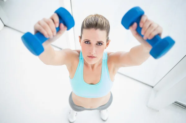 Concentrated woman in sportswear exercising with dumbbells — Stock Photo, Image