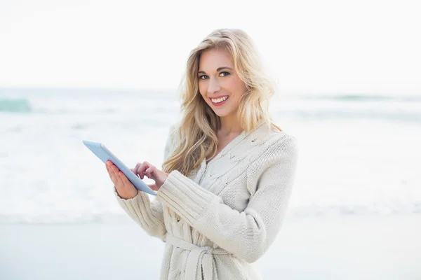 Cheerful blonde woman in wool cardigan using a tablet pc — Stock Photo, Image