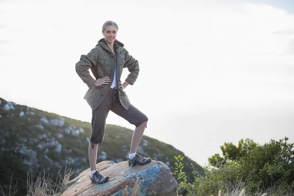 Woman standing on stone with hands on hips — Stock Photo, Image