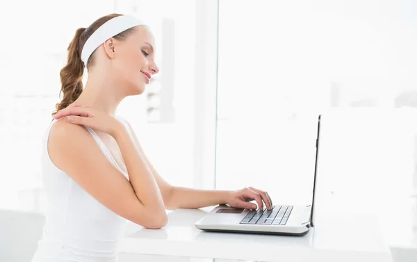 Concentrated pretty sportswoman typing on a laptop — Stock Photo, Image