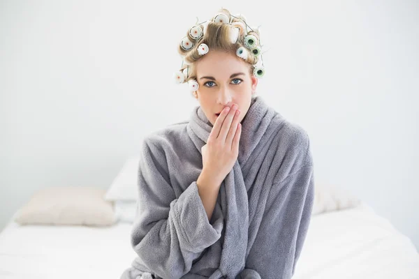 Attractive relaxed blonde woman in hair curlers yawning — Stock Photo, Image