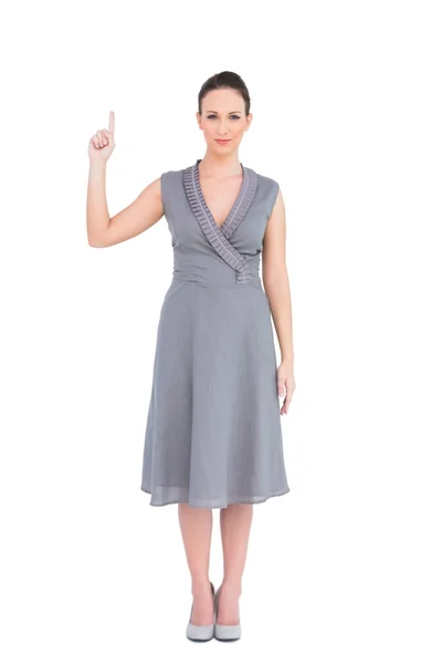 Mujer elegante pacífica en vestido con clase señalando el dedo hacia arriba — Foto de Stock