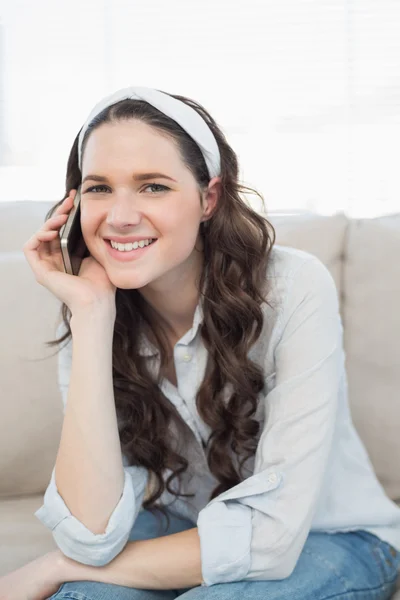 Smiling casual woman sitting on a cosy couch having a phone call — Stock Photo, Image