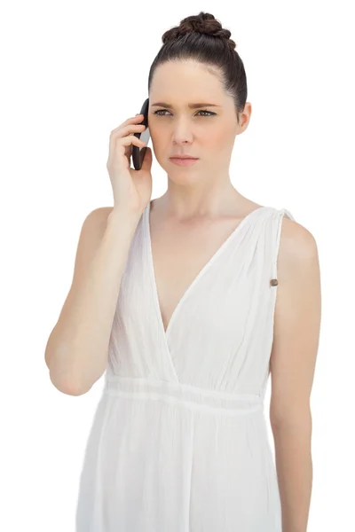 Serious pretty model in white dress having phone call — Stock Photo, Image