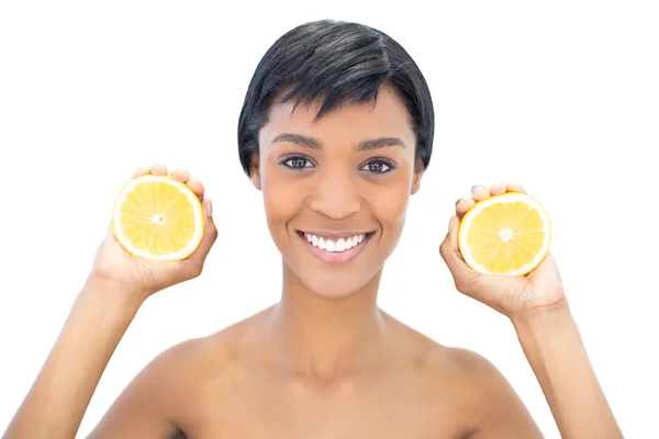 Mulher de cabelos pretos agradável segurando duas metades de uma laranja — Fotografia de Stock