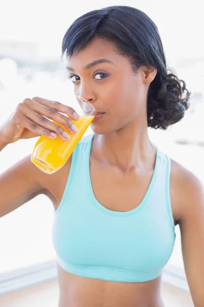 Mulher pensativo ajuste bebendo um copo de suco de laranja — Fotografia de Stock