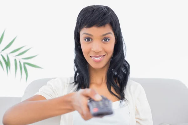 Glimlachend zwarte haired vrouw in witte kleren chaning tv-zender — Stockfoto