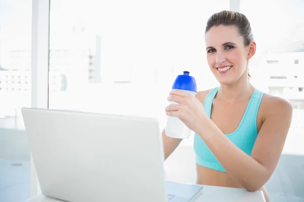 Smiling blonde woman in sportswear holding flask — Stock Photo, Image