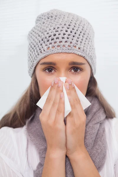 Morena com chapéu de inverno em soprar o nariz — Fotografia de Stock