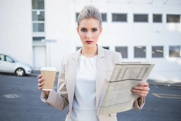 Stern stylish businesswoman holding newspaper and coffee — Stock Photo, Image