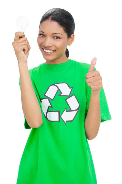 Smiling model wearing recycling tshirt holding light bulb — Stock Photo, Image