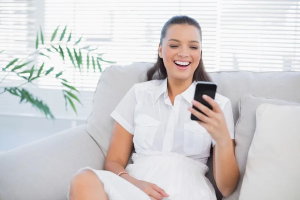 Glückliche Frau blickt auf ihr Handy und lacht — Stockfoto