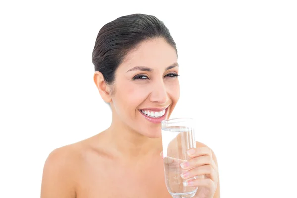 Bruna sorridente che tiene un bicchiere d'acqua e guarda la fotocamera — Foto Stock