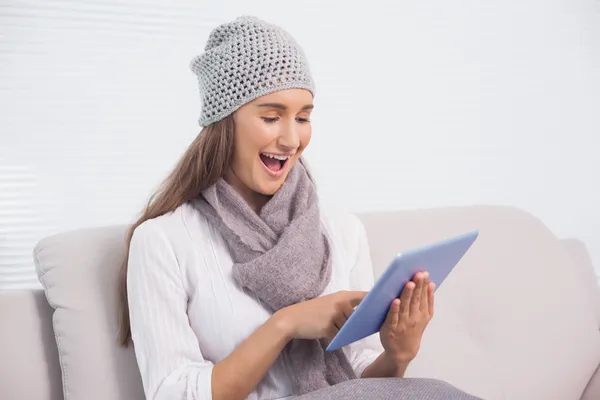 Cheerful cute brunette with winter hat on scrolling on her tablet — Stock Photo, Image