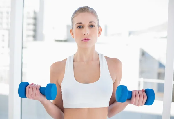 Attentive young blonde model exercising with dumbbells — Stock Photo, Image
