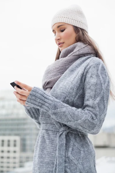 Focused brunette with winter clothes on text messaging — Stock Photo, Image