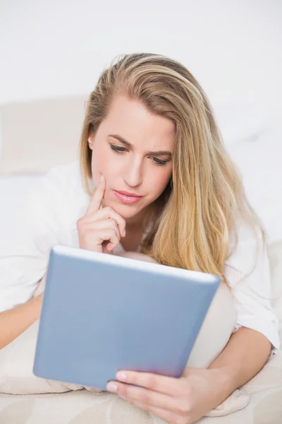 Concentrated model using her tablet lying on cosy bed — Stock Photo, Image