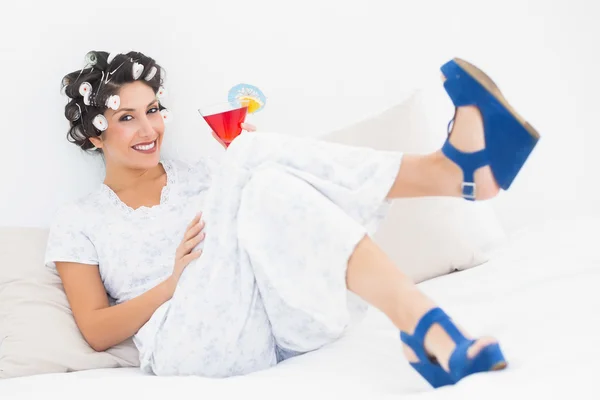 Brunette in hair curlers and wedge shoes holding a cocktail — Stock Photo, Image