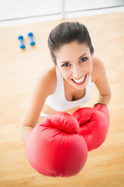 Přizpůsobit žena nosí červené Boxerské rukavice se usmívá na kameru — Stock fotografie