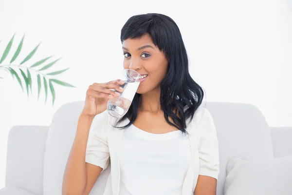 Mujer de pelo negro divertida en ropa blanca disfrutando de un vaso de agua —  Fotos de Stock