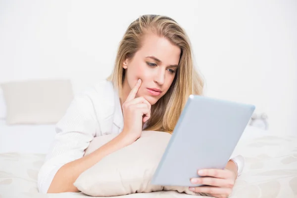 Fokussiert hübsches Modell mit ihrem Tablet auf gemütlichem Bett liegend — Stockfoto