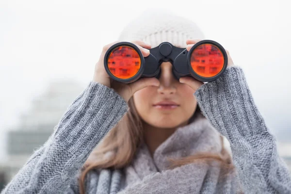 Nette Frau mit Winterkleidung beim Blick durchs Fernglas — Stockfoto