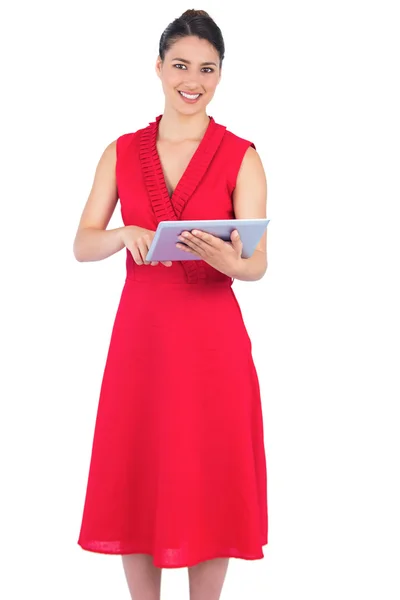 Sonriendo elegante morena en vestido rojo sosteniendo la tableta pc — Foto de Stock