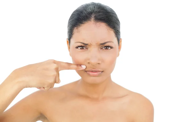 Frowning black haired model pointing above her lips — Stock Photo, Image