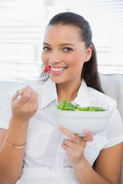 Wesoły ładny kobieta jedzenie zdrowe sałatki siedzi na kanapie — Zdjęcie stockowe
