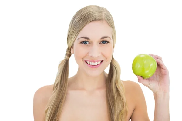 Pleased young blonde woman holding a green apple — Stock Photo, Image