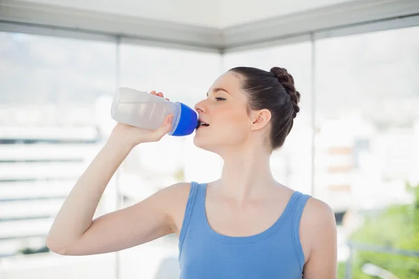 Ganska vältränad kvinna dricksvatten på hennes plast kolv — Stockfoto