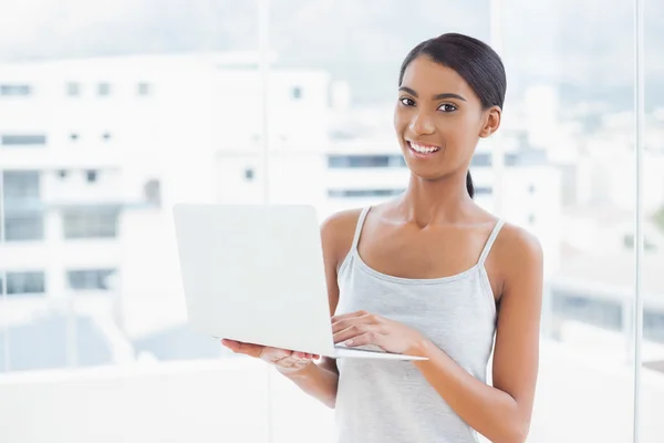 Smiling sporty model using her laptop — Stock Photo, Image