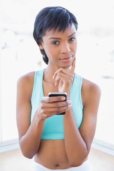 Thoughtful black haired woman holding a mobile phone — Stock Photo, Image