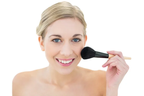 Pleased young blonde woman applying powder on her cheek — Stock Photo, Image
