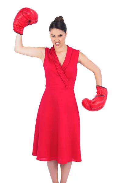 Irritado linda morena em vestido vermelho usando luvas de boxe — Fotografia de Stock