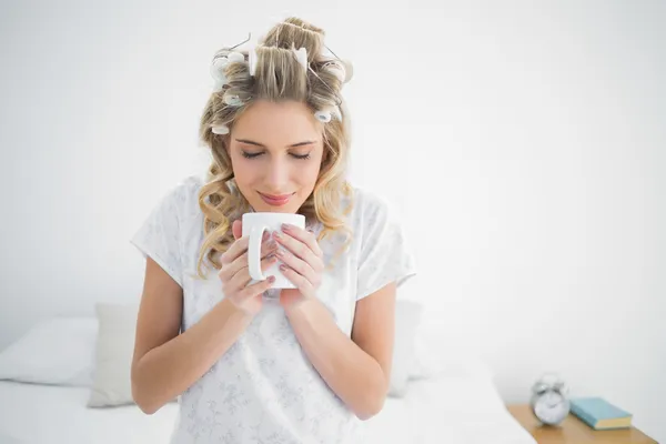 Huzurlu tatlı bir sarışın saç curlers kahve kokulu giyiyor — Stok fotoğraf