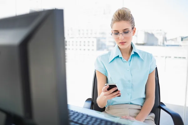 Focused businesswoman wearing glasses text messaging — Stock Photo, Image