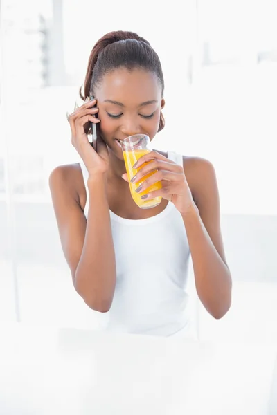 Mulher atlética feliz telefonando enquanto bebe suco de laranja — Fotografia de Stock