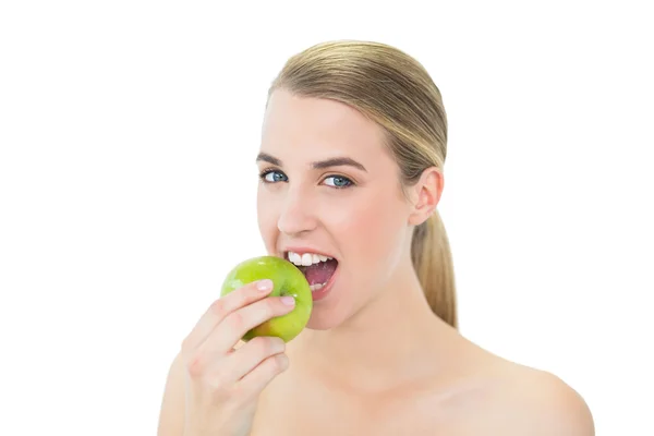 Smiling attractive blonde eating green apple — Stock Photo, Image