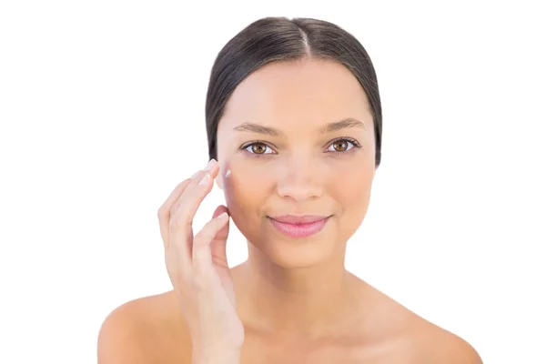 Donna sorridente diffusione crema di bellezza sulla guancia — Foto Stock