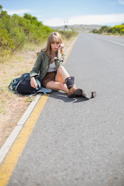 Cansada rubia bonita sentada en el borde de la carretera —  Fotos de Stock