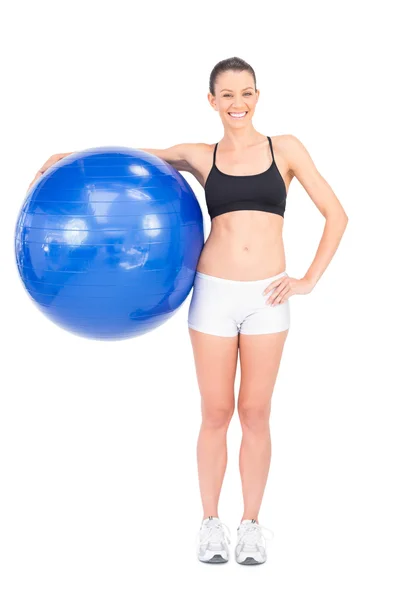 Mujer en forma sosteniendo bola de ejercicio sonriendo a la cámara — Foto de Stock