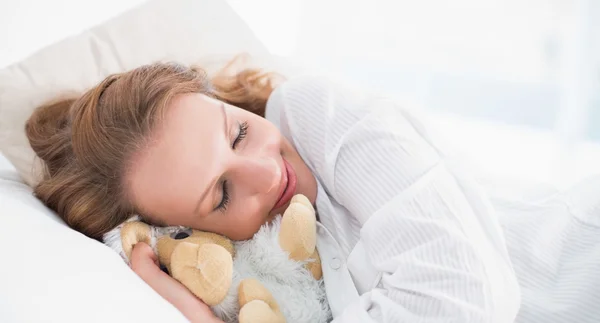 Lächelnde hübsche schlafende Frau umarmt ein Plüschschaf — Stockfoto
